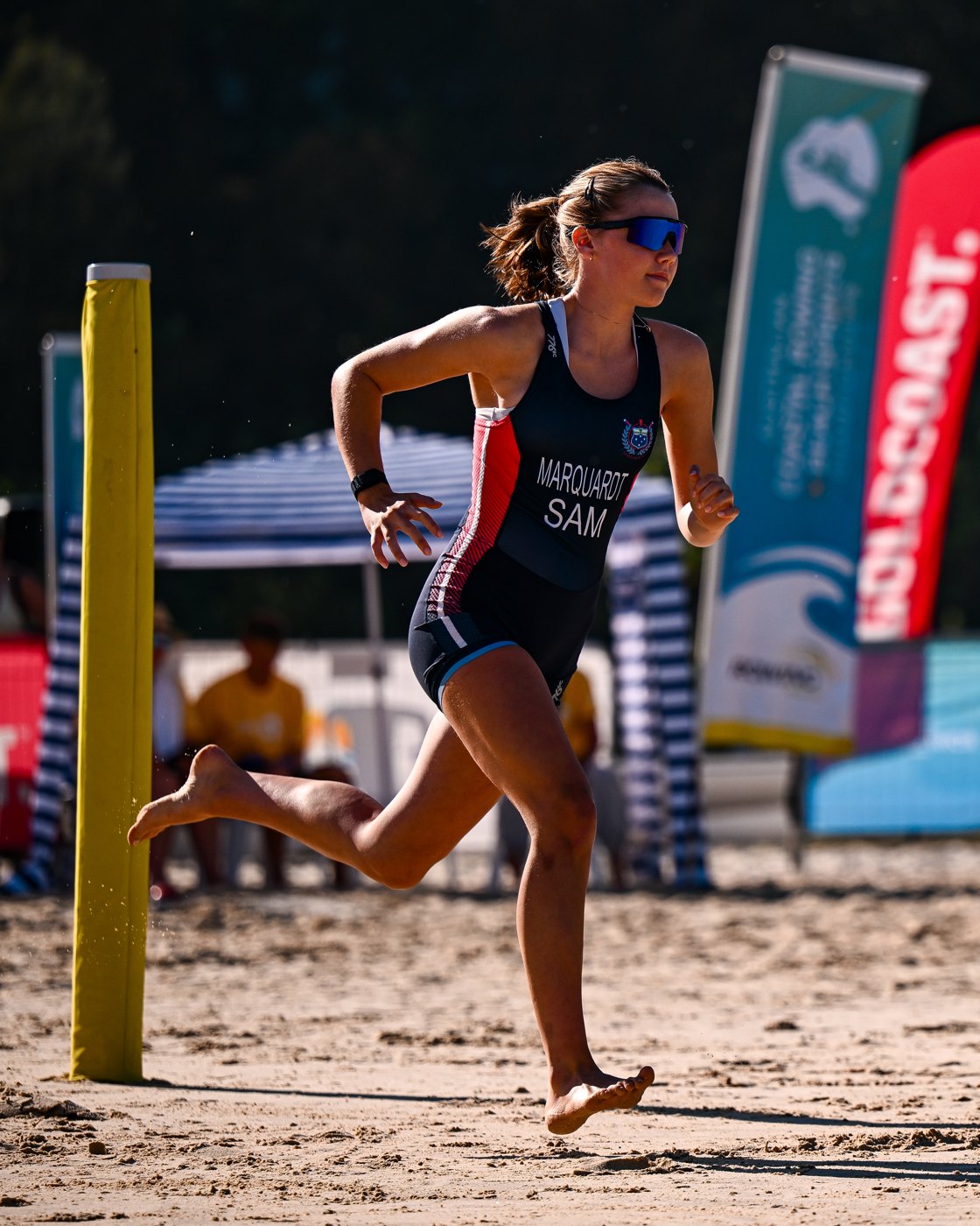 Alia Marquardt sprinting past the finish post in the Samoa unisuit, championship banners behind her