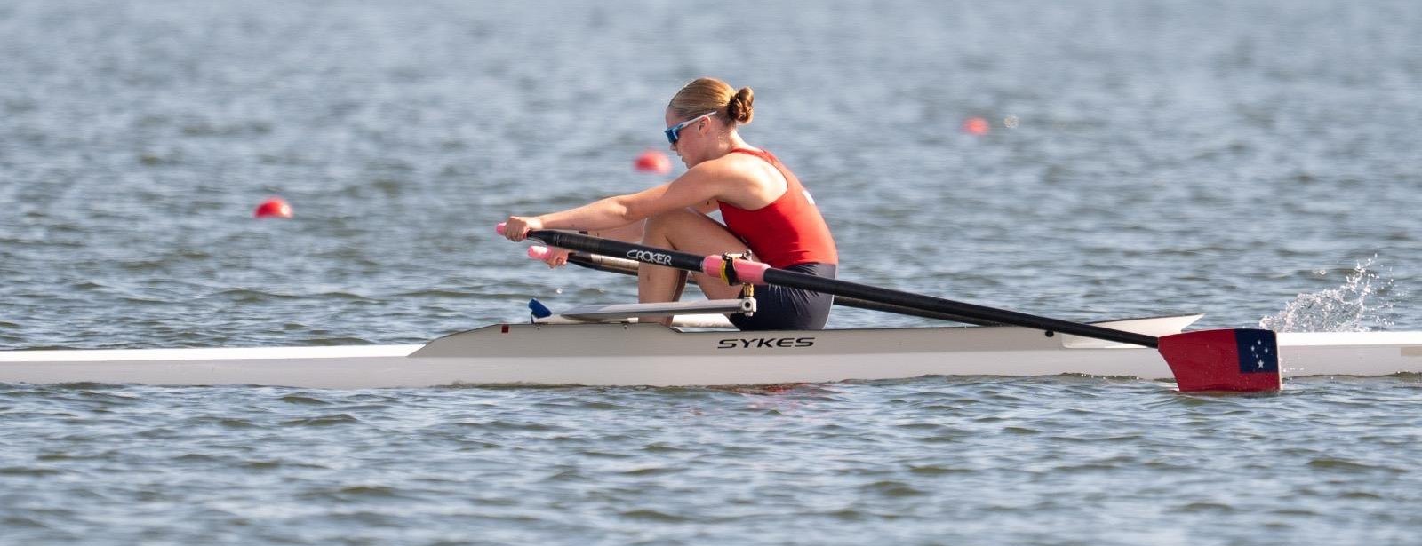 Alia Marquardt sculling at the catch in a single, the Samoan flag on her blade